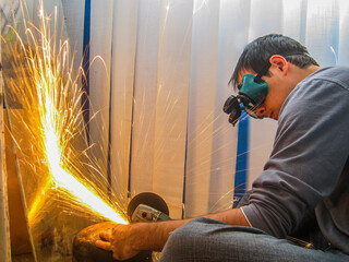 A guy saws metal with sparks with a grinder	
