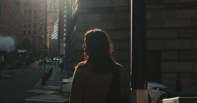 Woman standing at the crosswalk and looks around in cinematic urban New York City street.