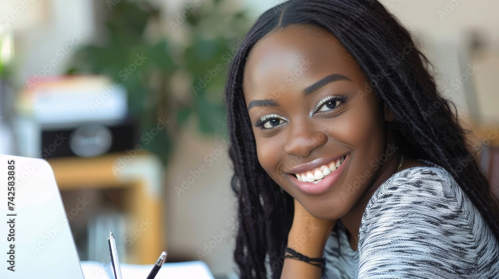 Poster smiling black woman working on laptop, taking notes in notebook, studying online, watching webinar, 
