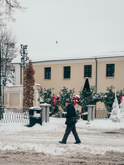 An old man walks along a snowy street in the Vilnius center