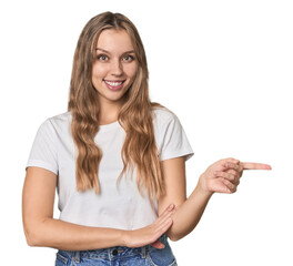 Obraz premium Studio portrait of a blonde Caucasian woman smiling cheerfully pointing with forefinger away.