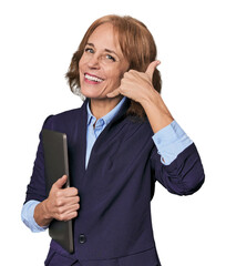 Mid-aged Caucasian with laptop in studio showing a mobile phone call gesture with fingers.