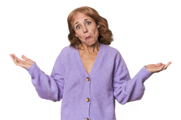 Redhead mid-aged Caucasian woman in studio doubting and shrugging shoulders in questioning gesture.