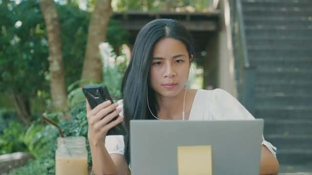 Young asian woman feel relax sitting on coffee table using smartphone shopping online, online transactions via laptop computer download and upload posting pictures on social media, internet influencer