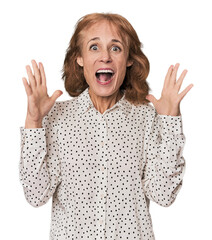 Redhead mid-aged Caucasian woman in studio celebrating a victory or success, he is surprised and shocked.