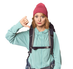 Middle-aged Caucasian woman with hiking gear showing a dislike gesture, thumbs down. Disagreement...