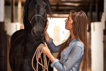 Foto op Canvas Barn, woman and horse in stable for bonding, sports training or sustainable farming in Texas with rope. Stallion, person and cowgirl with animal on farm or ranch for healthy livestock, hobby and care © Y.A./peopleimages.com