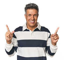Middle-aged Latino man indicates with both fore fingers up showing a blank space.