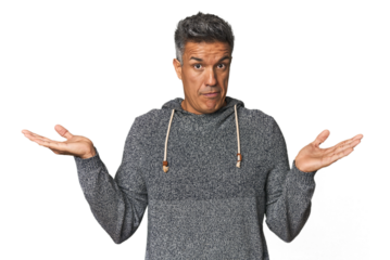 Middle-aged Latino man confused and doubtful shrugging shoulders to hold a copy space.