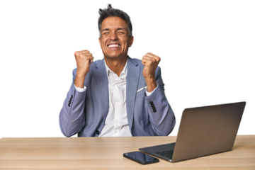 Elegant businessman at desk with laptop cheering carefree and excited. Victory concept.