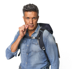 Hispanic hiker with backpack and flask with fingers on lips keeping a secret.