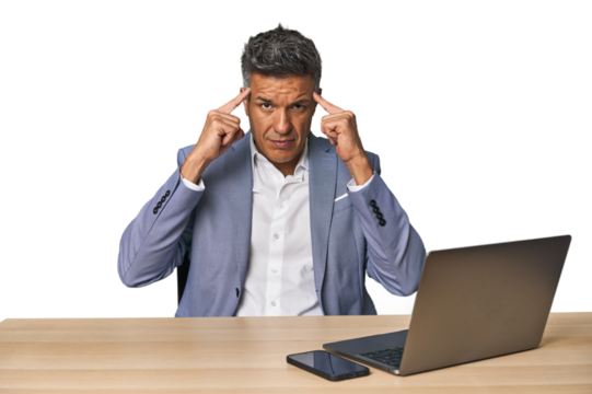 Elegant businessman at desk with laptop focused on a task, keeping forefingers pointing head.