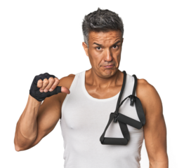 Athletic middle-aged Hispanic with resistance bands showing a dislike gesture, thumbs down. Disagreement concept.