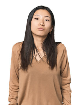Young Chinese woman in studio setting shrugs shoulders and open eyes confused.