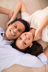 Fototapeta na wymiar Portrait, smile and top view of couple on floor, holding hands and relax together in home. Above, man and face of happy woman bonding for connection, love or support for healthy relationship in house