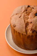 Delicious sweet holiday panettone cake with zest and raisins on a ceramic plate