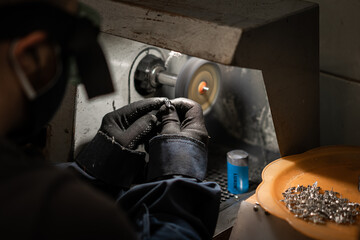 Lapidary worker polishing boulder precious stone or metal. no face, unrecognizable person.