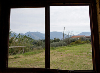 Window overlooking the mountaintop with old window frame and pane in front of a field.. 