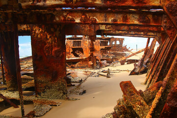 Rusty crumbling piece of the SS Maheno shipwreck half buried in the sand of the 75 mile beach on...