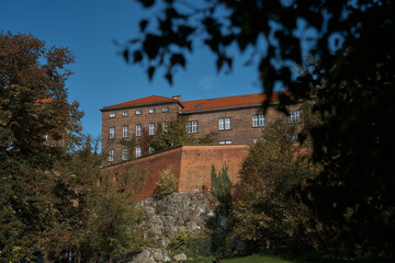 view of the Krakow Castle among the trees from the embankment alley