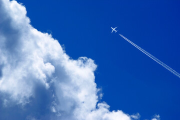 a passenger plane with vapour trails high in the blue sky