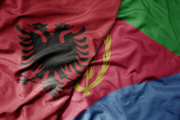 big waving national colorful flag of eritrea and national flag of albania .