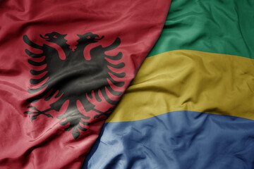 big waving national colorful flag of gabon and national flag of albania .