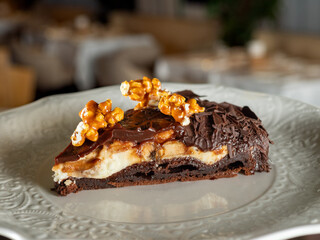 Delicious peanut and caramel cake with chocolate and walnut topped on white plate background. Piece...