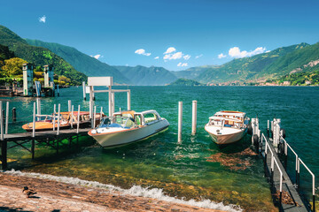 Lake Como (Italian Lago di Como) in summer. Docked motor boats and yachts at pier. Colorful...