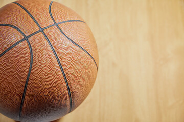 A basketball ball lies on a light basketball parquet, close-up