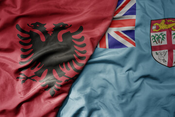 big waving national colorful flag of Fiji and national flag of albania .