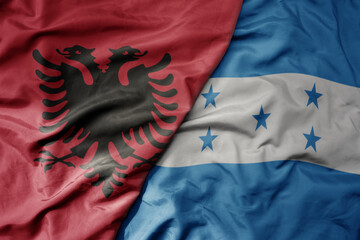 big waving national colorful flag of honduras and national flag of albania .
