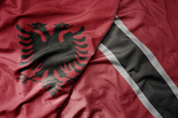 big waving national colorful flag of trinidad and tobago and national flag of albania .