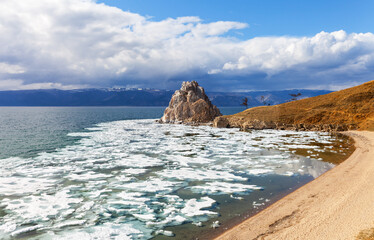 Picturesque landscape of Baikal Lake in spring. View of the famous Shamanka Rock - a natural landmark of Olkhon Island during the May ice drift. Spring travel and recreation. Natural background