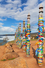 Baikal Lake in Spring sunny day. Sacred place near Khuzhir village on Olkhon Island.  On famous Cape Burhan, tourists tie colorful ribbons to poles and make wishes. Ice drift in Sarayskiy Bay