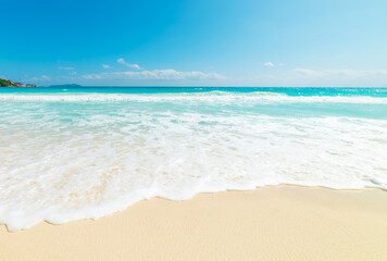 White waves in a tropical beach with turquoise water and golden sand