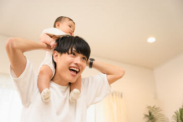 笑顔で0歳の赤ちゃんを肩車で楽しませる20代から30代の男性の父親