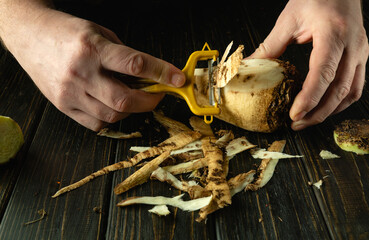 Close-up of a cook hands using a peeler to peel raw sugar beets to prepare lunch. Vegetable menu...