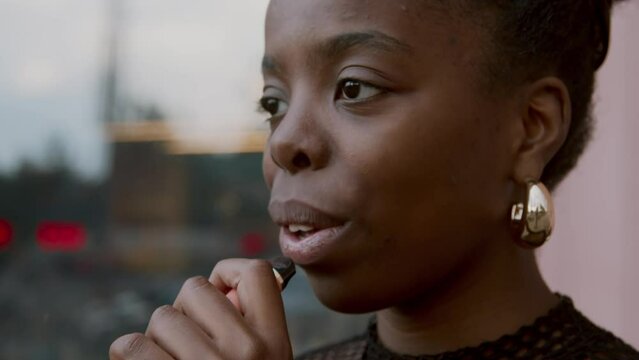 Close-up portrait shot footage of stylish young African American woman spending time outdoors vaping e-cigarette looking away