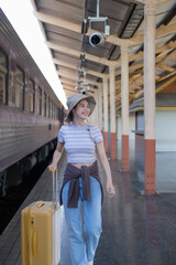 Naklejka premium Young woman with suitcase waits at the metro station while the train arrrives, Tourism and travel in the summer. Vacations for the student. Work and travel