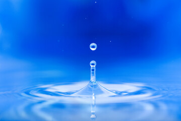 a drop of water jumps upwards from the water surface