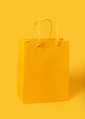 Yellow paper shopping bag on yellow background. Shopping sale delivery concept. Packaging gift.