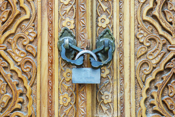 the metal barn lock on the wooden old carved door is closed 