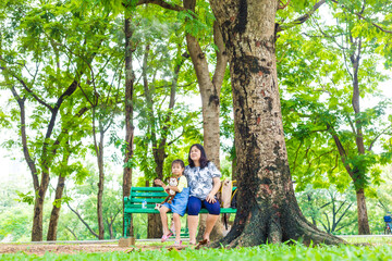 Adorable little asian daughter relax in city publice green park with mom - 742700694