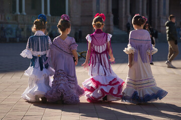 Four girls dancing flamenco, back to back, walking while talking, in typical flamenco costume in a nice square in Seville. Dance concept, flamenco, typical Spanish, Seville, Spain.