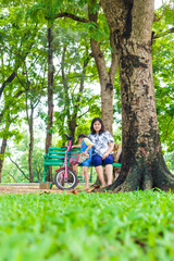 Adorable little asian daughter relax in city publice green park with mom - 742701019
