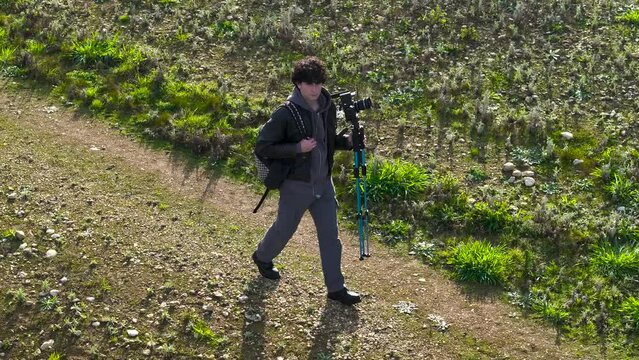 Man Walking On Field With Tripod And Digital Camera - Drone Shot