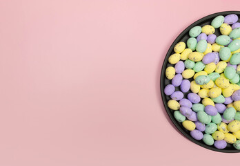 Top view of colourful easter eggs in black plate on pink background. Creative easter composition,...