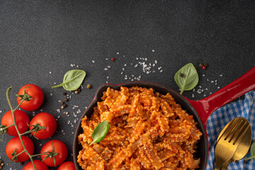 Mafaldine pasta with tomato sauce, italian bolognese, tomato marinara, vegan mushroom or eggplant sauce pasta on black concrete background, with ingredients and spices, copy space
