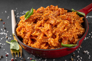 Mafaldine pasta with tomato sauce, italian bolognese, tomato marinara, vegan mushroom or eggplant sauce pasta on black concrete background, with ingredients and spices, copy space